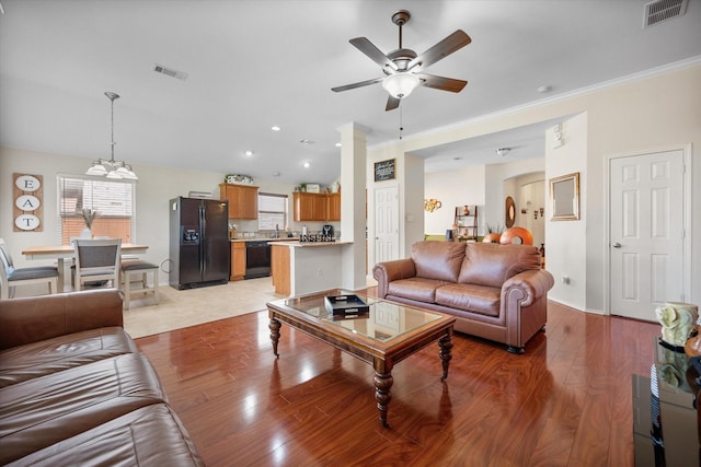 living room featuring a ceiling fan, healthy amount of natural light, light wood-type flooring, crown molding, and recessed lighting