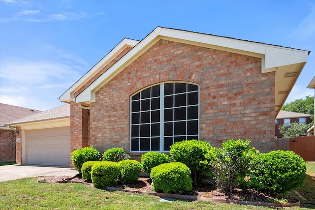 view of front facade with brick siding, a garage, concrete driveway, and fence