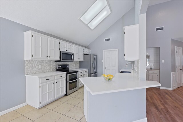 kitchen with stainless steel appliances, a sink, high vaulted ceiling, decorative backsplash, and white cabinetry