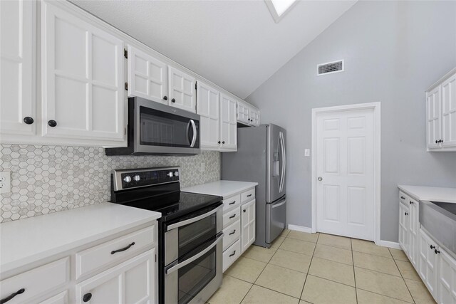 kitchen with stainless steel appliances, tasteful backsplash, white cabinets, light tile patterned floors, and light countertops