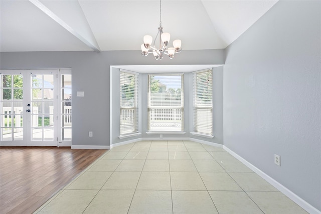 unfurnished dining area with lofted ceiling, a chandelier, plenty of natural light, and baseboards