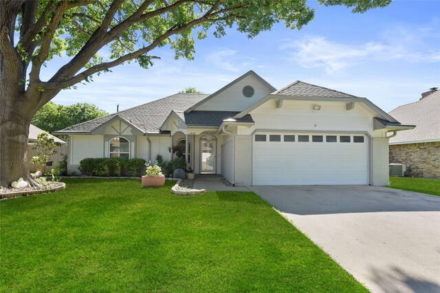 view of front of house featuring a garage, driveway, a front lawn, cooling unit, and brick siding
