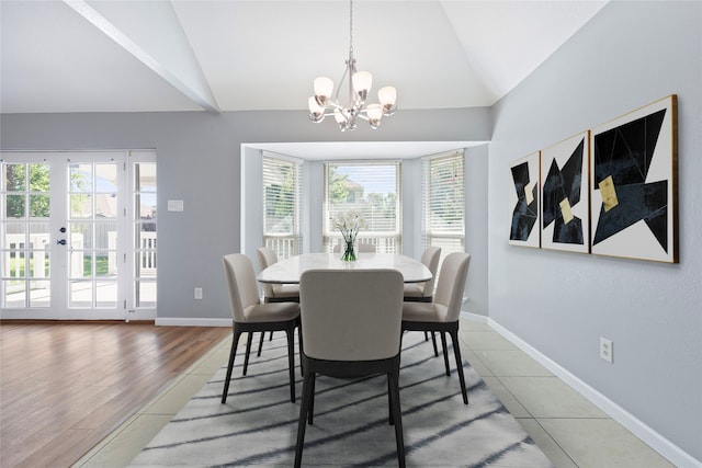 tiled dining space with vaulted ceiling, a chandelier, and baseboards