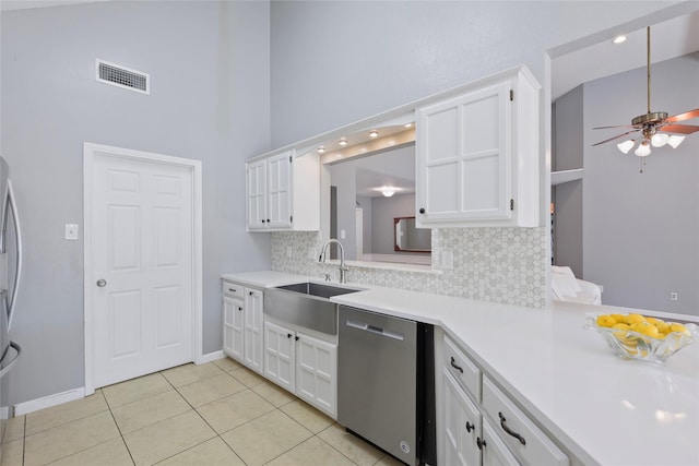 kitchen with stainless steel dishwasher, a sink, a ceiling fan, backsplash, and light countertops