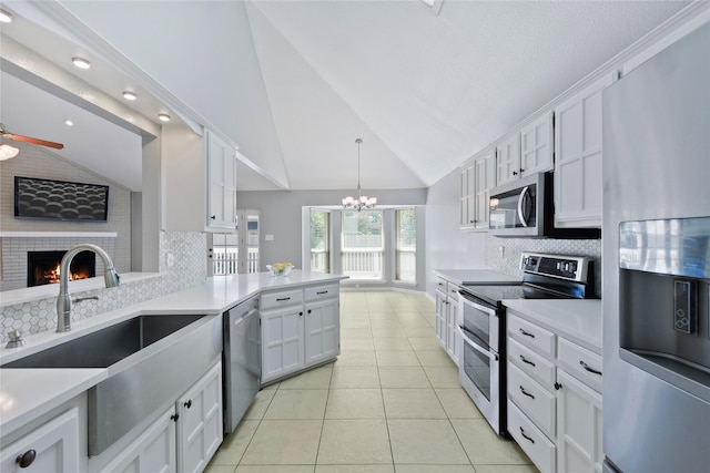 kitchen featuring appliances with stainless steel finishes, a sink, white cabinetry, tasteful backsplash, and high vaulted ceiling