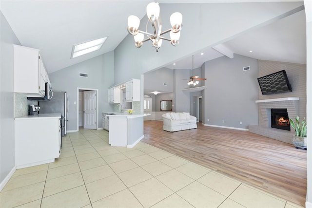 kitchen featuring open floor plan, high vaulted ceiling, light countertops, light tile patterned floors, and white cabinets