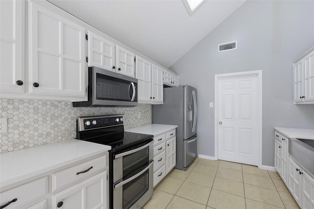 kitchen with appliances with stainless steel finishes, tasteful backsplash, white cabinets, light tile patterned floors, and light countertops