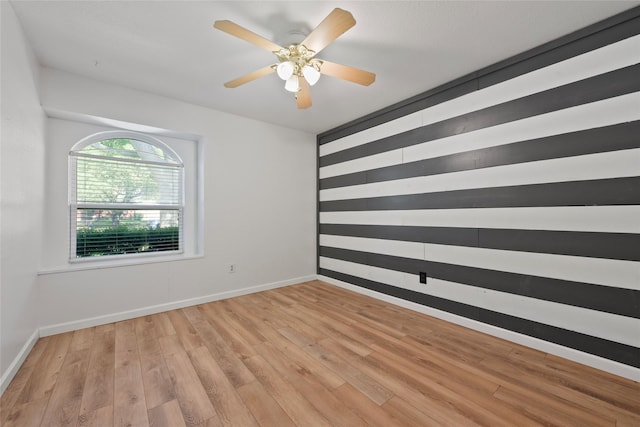empty room featuring light wood-type flooring, baseboards, and a ceiling fan