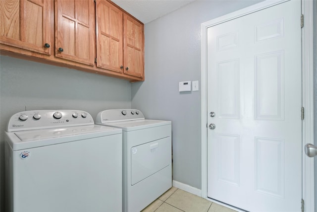 washroom with cabinet space, independent washer and dryer, light tile patterned floors, a textured ceiling, and baseboards