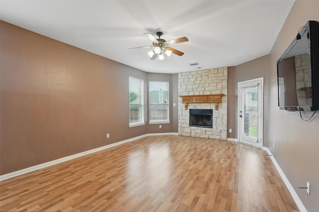 unfurnished living room with light wood-type flooring, plenty of natural light, a ceiling fan, and baseboards
