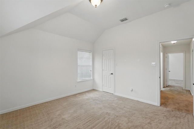 unfurnished bedroom featuring light colored carpet, lofted ceiling, and baseboards