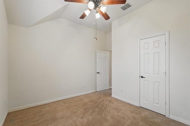 spare room with vaulted ceiling, a ceiling fan, light colored carpet, and baseboards
