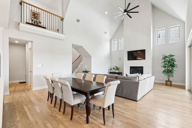 13417 Meadow Cross Dr, Fort Worth, TX 76008 - dining room with high vaulted ceiling, stairs, light wood-style flooring, ceiling fan, and a fireplace