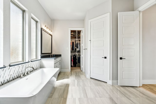 13417 Meadow Cross Dr, Fort Worth, TX 76008 - bathroom featuring a soaking tub, vanity, a spacious closet, and baseboards