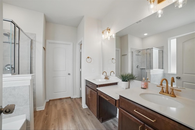 bathroom featuring a stall shower, wood finished floors, and double vanity
