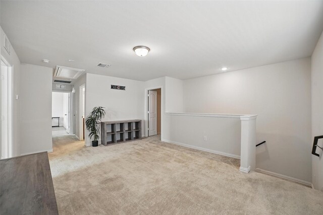 unfurnished living room featuring attic access, carpet floors, and baseboards