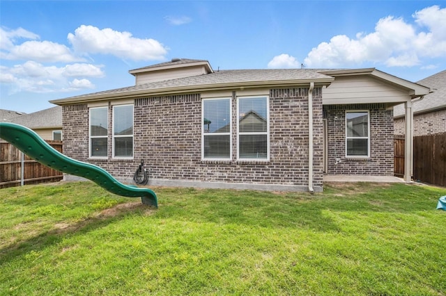rear view of property with brick siding and a playground