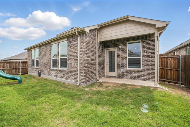 rear view of house with brick siding and a playground