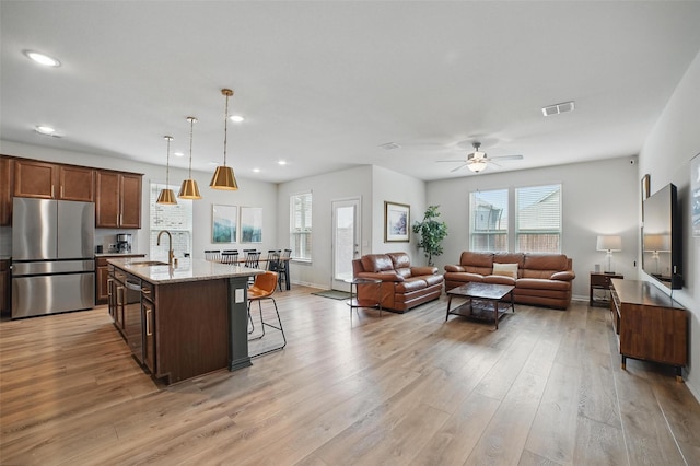 living room with a ceiling fan, plenty of natural light, light wood finished floors, recessed lighting, and baseboards