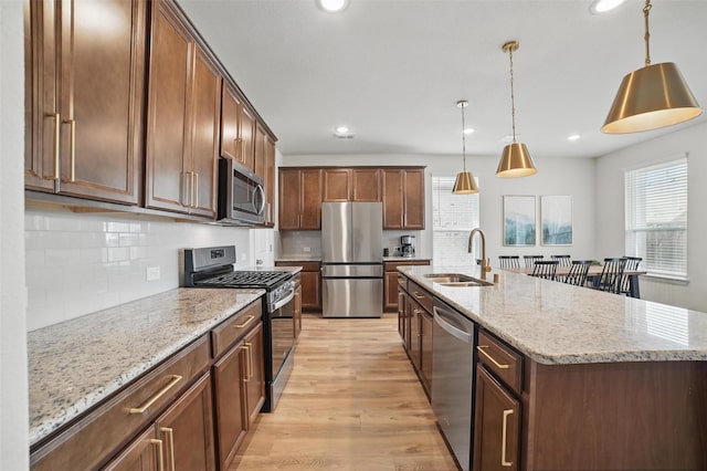 kitchen with a sink, appliances with stainless steel finishes, light wood-style flooring, backsplash, and recessed lighting