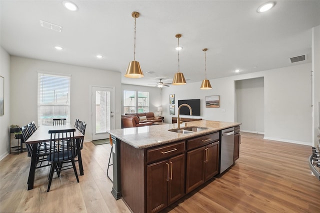kitchen with stainless steel dishwasher, a sink, light wood-style floors, decorative light fixtures, and recessed lighting
