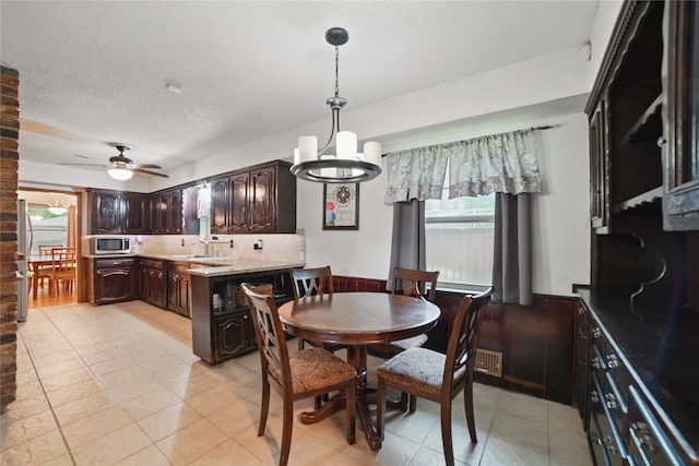 4548 Ivy Dr, Mesquite, TX 75150 - dining area featuring a chandelier, ceiling fan, light tile patterned floors, a textured ceiling, and a wainscoted wall