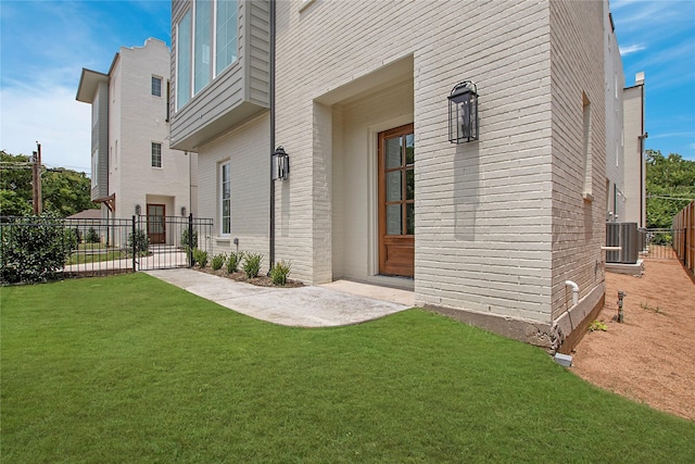 doorway to property with central air condition unit, a gate, and brick siding