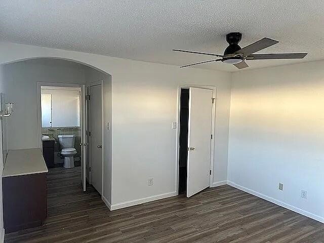 5817 Sandhurst Ln Unit B, Dallas, TX 75206 - unfurnished bedroom with arched walkways, dark wood finished floors, a textured ceiling, a closet, and baseboards