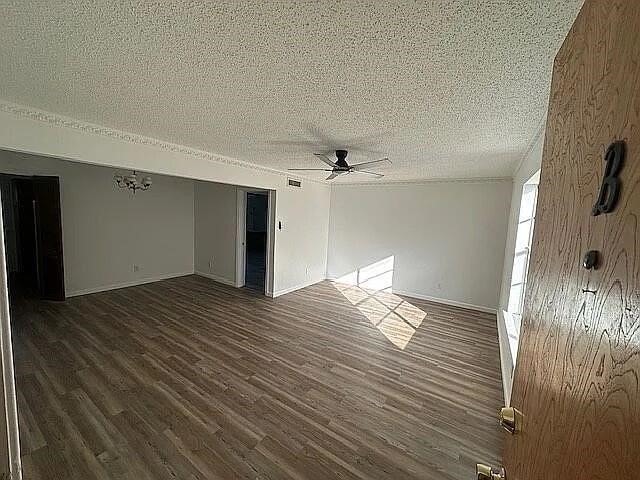 5817 Sandhurst Ln Unit B, Dallas, TX 75206 - spare room featuring a textured ceiling, a ceiling fan, dark wood-style floors, and baseboards