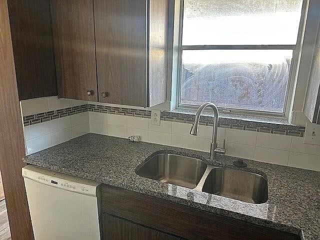 5817 Sandhurst Ln Unit B, Dallas, TX 75206 - kitchen with white dishwasher, a sink, decorative backsplash, and dark brown cabinets