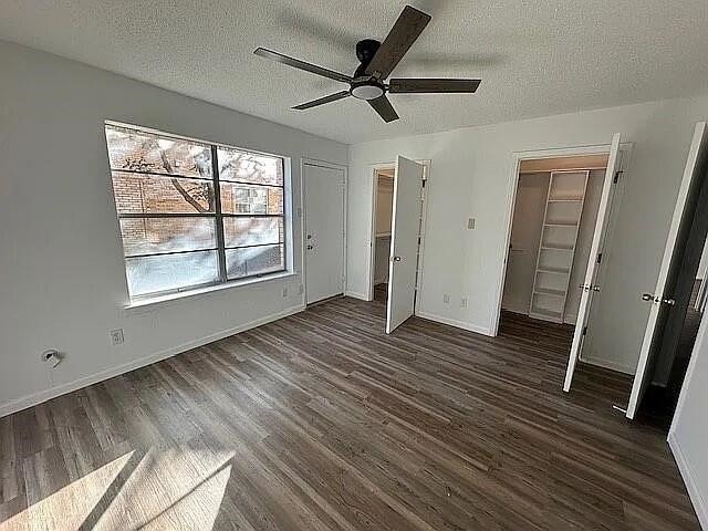 5817 Sandhurst Ln Unit B, Dallas, TX 75206 - unfurnished bedroom with a textured ceiling, dark wood-style floors, baseboards, and a ceiling fan