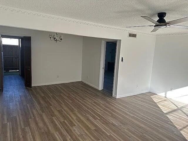 5817 Sandhurst Ln Unit B, Dallas, TX 75206 - spare room with a textured ceiling, dark wood-type flooring, ceiling fan, baseboards, and a chandelier