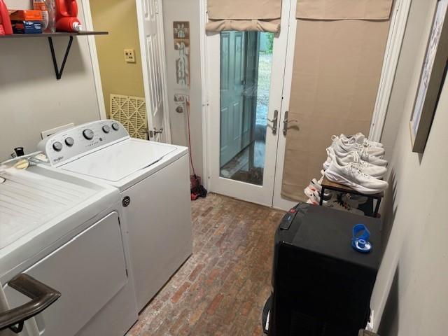 clothes washing area featuring separate washer and dryer, brick flooring, and french doors