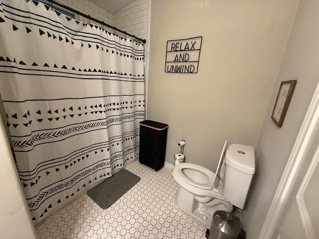 full bath with toilet and a shower with shower curtain