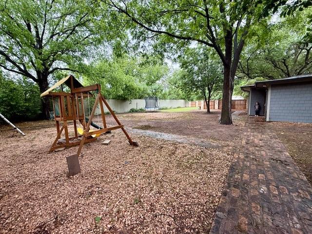 view of playground with fence and view of wooded area