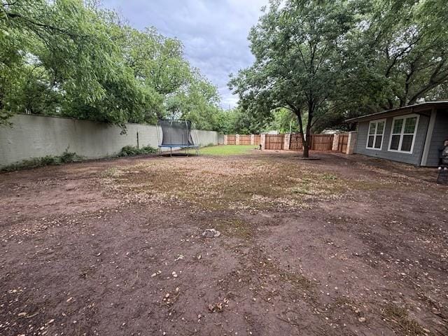 fenced backyard featuring a trampoline