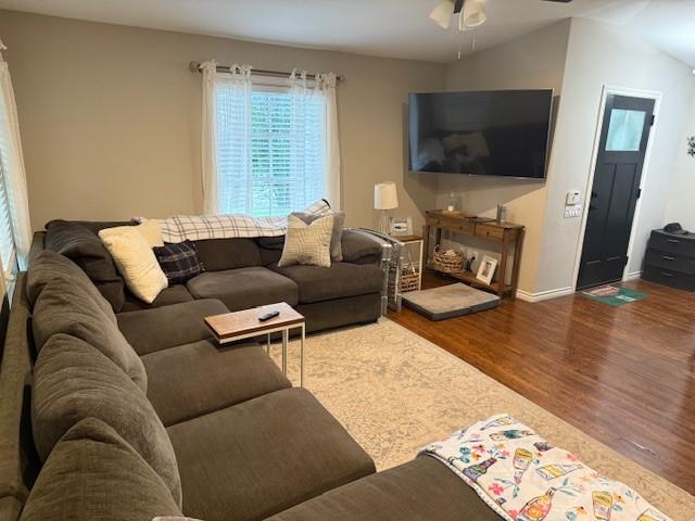 living area featuring wood finished floors, a ceiling fan, and baseboards