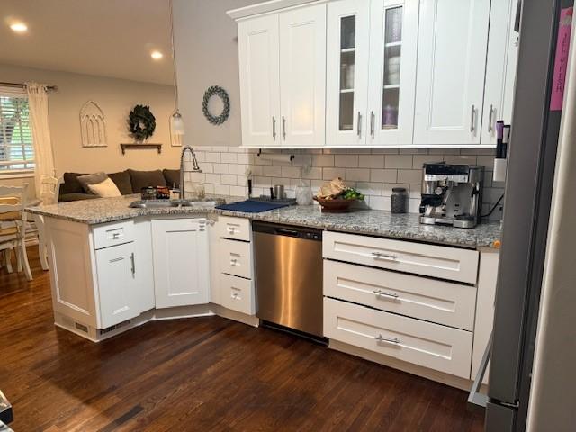 kitchen with stainless steel appliances, a peninsula, a sink, glass insert cabinets, and white cabinetry
