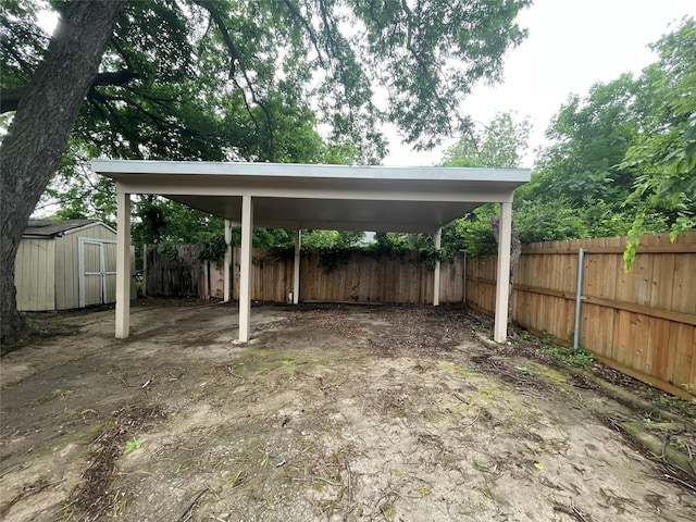 view of yard with fence, a shed, an outbuilding, a carport, and driveway
