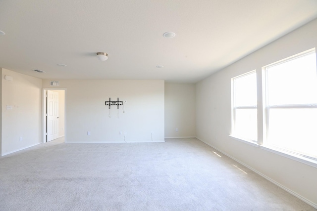 empty room featuring baseboards and light carpet