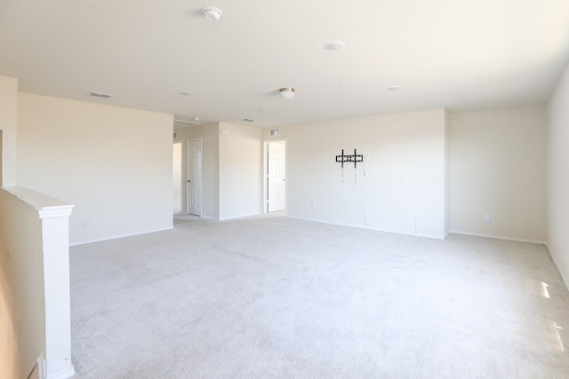 empty room with a smoke detector, light carpet, and baseboards