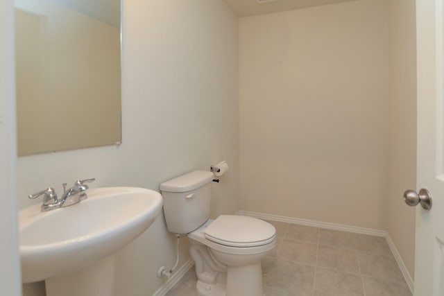 bathroom featuring a sink, toilet, baseboards, and tile patterned floors