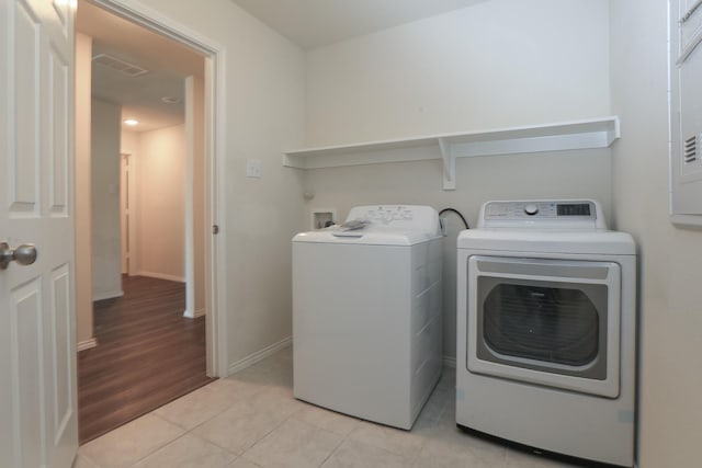 washroom with separate washer and dryer, light tile patterned floors, and baseboards