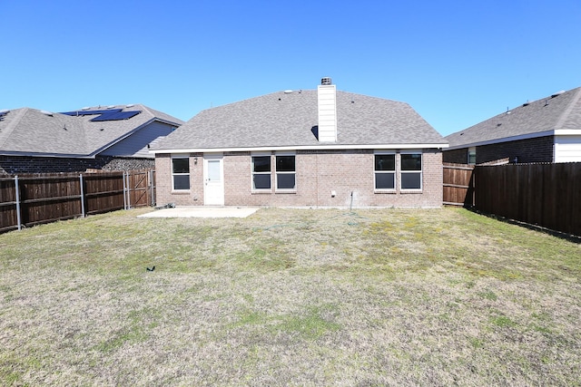 rear view of house featuring brick siding, a chimney, a patio, and roof with shingles