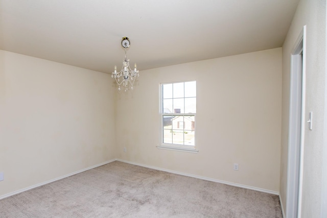 spare room with a chandelier, light colored carpet, and baseboards