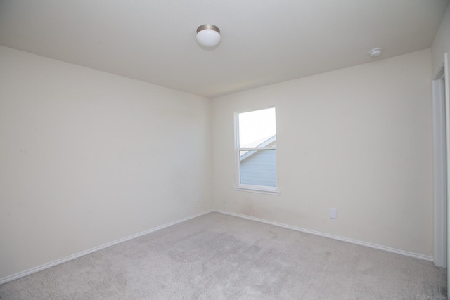 unfurnished room with light colored carpet, baseboards, and a smoke detector