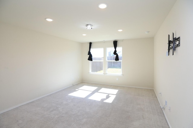 empty room featuring light colored carpet, recessed lighting, and baseboards
