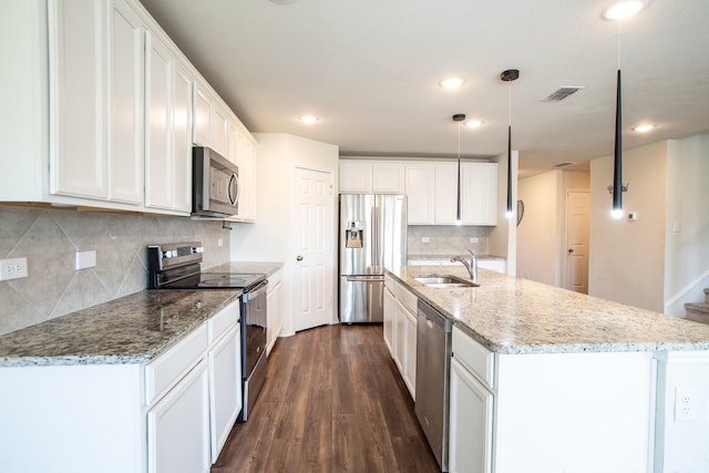 kitchen with stainless steel appliances, a sink, dark wood-style flooring, white cabinetry, and decorative backsplash