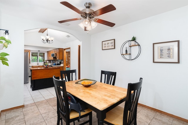dining space with arched walkways, baseboards, ceiling fan, a chandelier, and light tile patterned floors