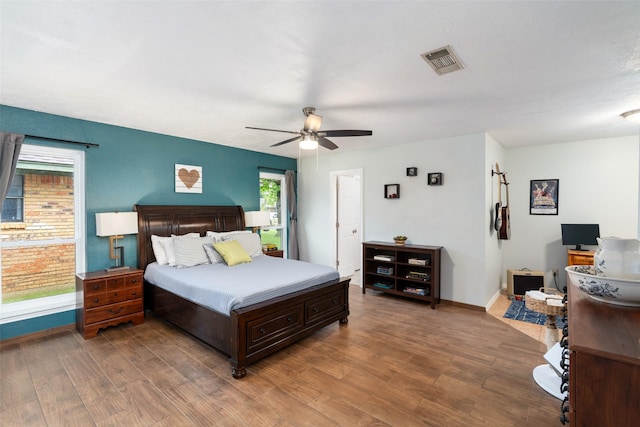 bedroom with wood finished floors, multiple windows, baseboards, and ceiling fan